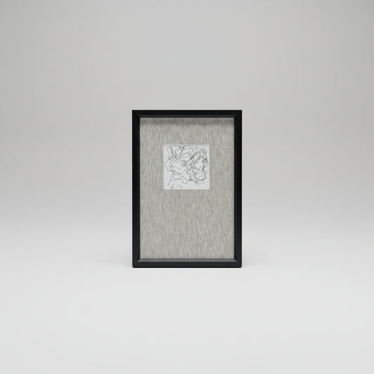 A framed artwork featuring a white scribble face on a black background, placed on a wooden surface with a plant in the background.