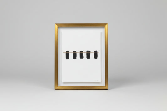 A framed artwork featuring a thin line segmented into four parts, displayed on a wooden surface with a black frame and a shadow falling on the wall.