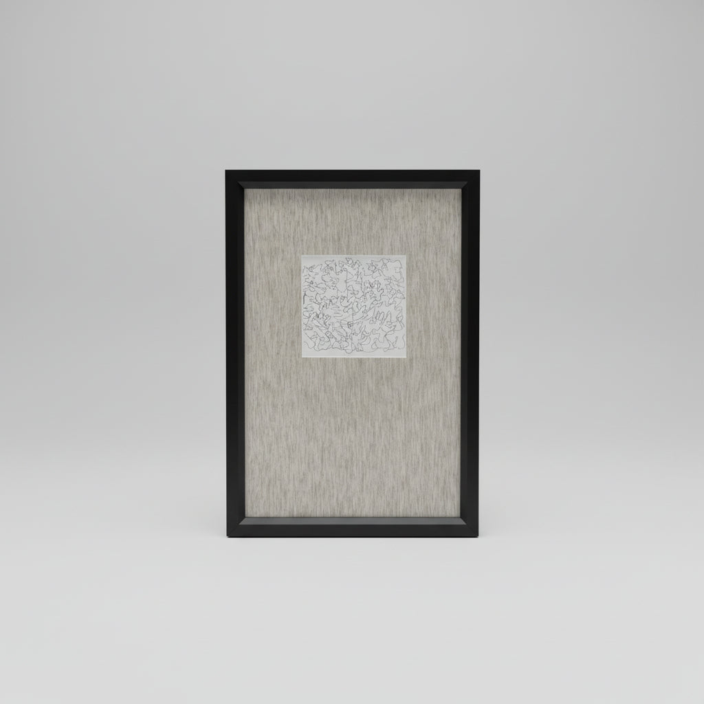 A framed artwork featuring a white background with black scribbles, displayed on a wooden surface with a black vase and a white curtain in the background.