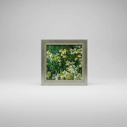 An acrylic painting on panel depicting a field of daisies, framed in a beige frame, displayed on a wall.