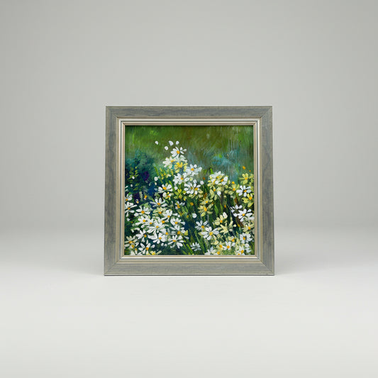 An acrylic painting of daisies in a frame, displayed on a wall.
