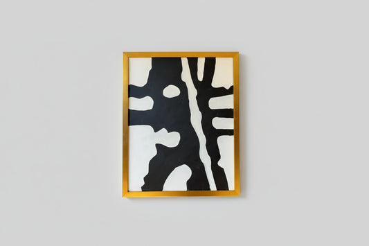 An abstract artwork with black and white colors and a custom gold frame, displayed on a wall.