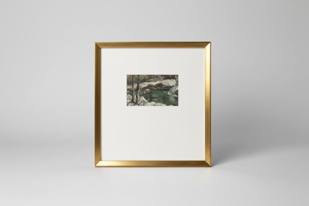 An oil on board painting depicting a winter river scene, framed in a gold frame, displayed against a wall with plants on either side.
